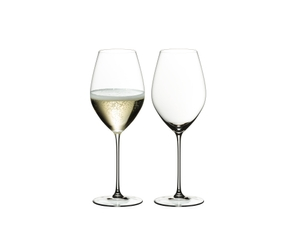Two RIEDEL Veritas Champagne Wine Glasses one filled with champagne and one unfilled on a transparent background. 