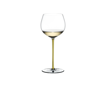 A RIEDEL Fatto A Mano Oaked Chardonnay glass in yellow filled with white wine on a transparent background. 