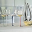 A RIEDEL Fatto A Mano Oaked Chardonnay glass in white filled with white wine on a white background. 