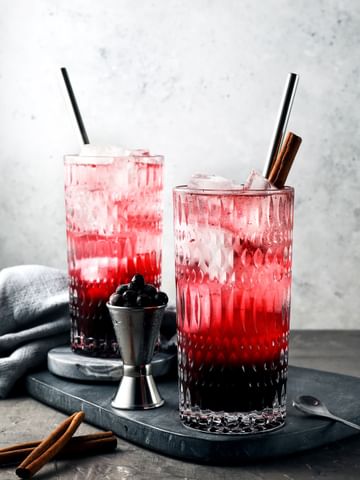 Two long drink glasses from the NACHTMANN Ethno series, filled with a black and red cocktail