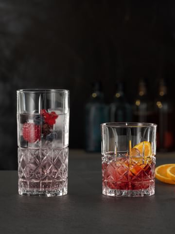 The NACHTMANN Highland Diamond longdrink glass filled with a berry cocktail on ice next to the Highland Diamond tumbler filled with a Negroni.<br/>