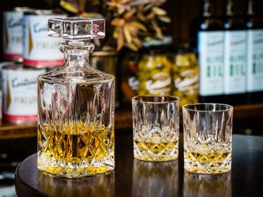 The Nachtmann Noblesse Whisky Set filled with Whisky on a glass table top.
