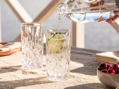 Two NACHTMANN Noblesse long drink glasses being filled with water