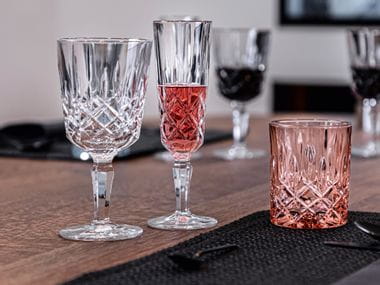 Il bicchiere da cocktail con stelo NACHTMANN Noblesse, accanto al bicchiere da Champagne rosé e al tumbler color rosé.<br/>