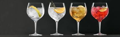 A row of SPIEGELAU Gin and tonic glasses filled with different nicely decorated gin based cocktails.<br/>
