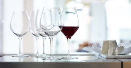 A mixed group of SPIEGELAU Bordeaux and Burgundy glasses on a sideboard. The Bordeaux glass is filled with red wine.<br/>