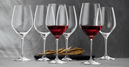 SPIEGELAU Superiore Bordeaux Bicchieri pieni di vino rosso. Sullo sfondo un vassoio nero con cracker.<br/>