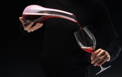 hands pouring wine from a decanter into a glass