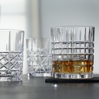 Die NACHTMANN Highland Becher in verschiedenen Schnittmustern, der Becher mit dem Quadratmuster gefüllt mit Whisky auf Eis.<br/>