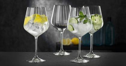 Four NACHTMANN Gin and Tonic glasses, three of them filled with different gin cocktails, one of them empty.<br/>