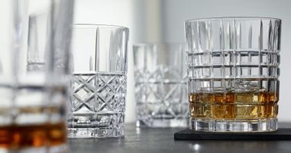 Die NACHTMANN Highland Becher in verschiedenen Schnittmustern, der Becher mit dem Quadratmuster gefüllt mit Whisky auf Eis.<br/>