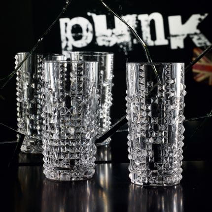 Zwei NACHTMANN Punk-Longdrink-Gläser auf einem schwarzen Tisch vor einem zerbrochenen Spiegel mit dem Schriftzug "Punk" und einem Wagenheber in diesem Spiegel.<br/>