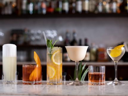 The RIEDEL Drink Specific Glassware Collection, lined up filled with cocktails on a bench.