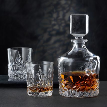 Die NACHTMANN Sculpture Whiskey-Karaffe neben dem NACHTMANN Sculpture Whiskey-Glas, beide gefüllt mit Whiskey. Im Hintergrund ein leerer Sculpture Becher auf einem Serviertablett.<br/>