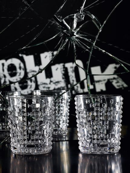 Two NACHTMANN Punk whisky tumblers on a black table in front of a broken mirror with the written word punk and a junion jack in this mirror.<br/>