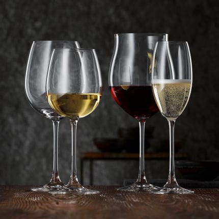 Le verre à vin blanc NACHTMANN Vivendi rempli de vin blanc à côté du verre à champagne rempli de champagne. Derrière eux se trouvent le verre à Bordeaux Vivendi vide et le verre à Bourgogne rempli de vin rouge.<br/>