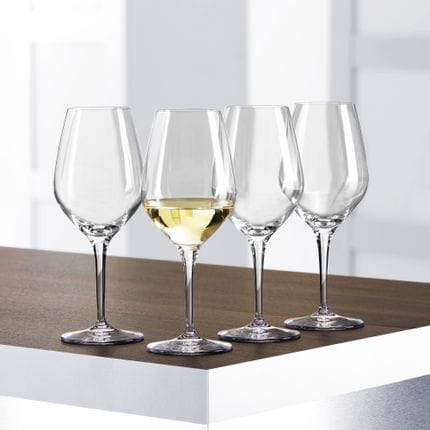 Vier SPIEGELAU Authentis Weißweingläser auf einem Tisch, eines davon ist mit Weißwein gefüllt.<br/>