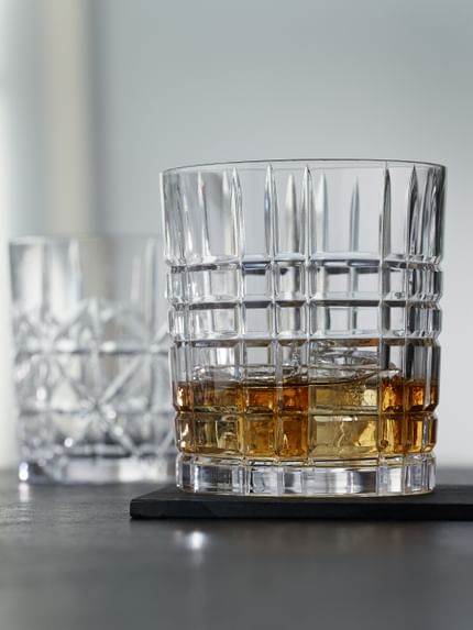 Die NACHTMANN Highland Becher in verschiedenen Schnittmustern, der Becher mit dem Quadratmuster gefüllt mit Whisky auf Eis.<br/>