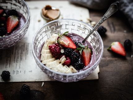 The NACHTMANN Bossa Nova food bowl filled with a purple cream smoothie with a fruit topping on it made of a sliced banana, blackberries and a strawberry cut in half.<br/>