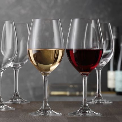 Un gruppo di bicchieri da vino bianco SPIEGELAU Festival su un tavolo. In primo piano un bicchiere è riempito di vino bianco e uno di vino rosso, a dimostrazione dell'uso universale di questi bicchieri.<br/>
