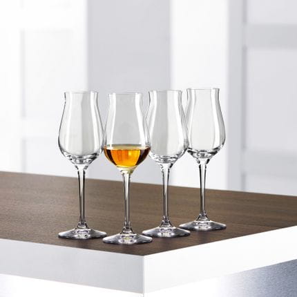 Four SPIEGELAU Authentis Digestive glasses on a table, one of them is filled with a golden brown liquor.<br/>