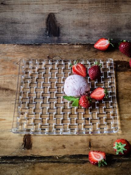 The NACHTMANN Bossa Nova square plate with ice cream and strawberris on a wooden table that is decorated with more strawberries.<br/>