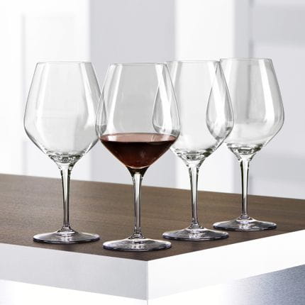 Cuatro copas de Borgoña SPIEGELAU Authentis sobre una mesa, una de ellas llena de vino de Borgoña.<br/>