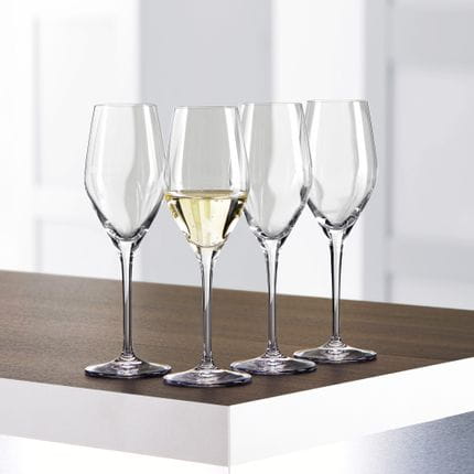 Four SPIEGELAU Authentis Champagne glasses on a table, one of them is filled with Champagne.<br/>