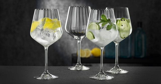 Quattro bicchieri NACHTMANN Gin and Tonic, tre dei quali riempiti con diversi cocktail a base di gin e uno vuoto.<br/>