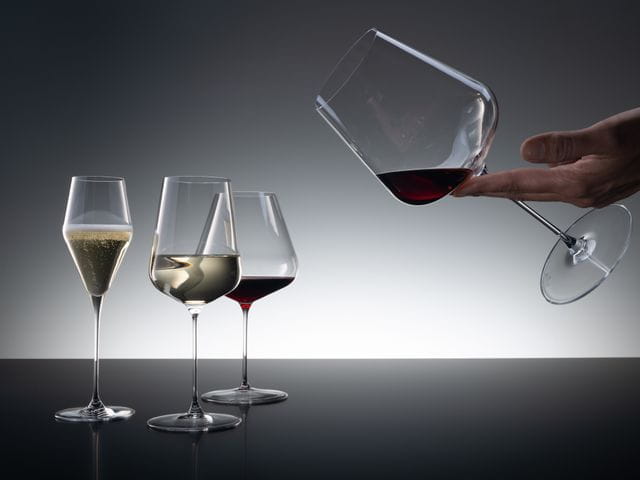 A group of three SPIEGELAU Definition glasses of which the Champagne glass is filled with sparkling wine, the Universal glass with white wine and the Burgundy glass with red wine.<br/>