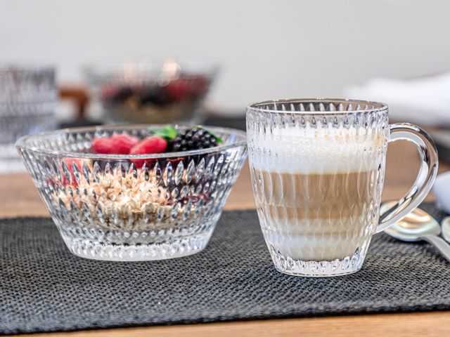 The NACHTMANN Ethno bowl filled with cereals and berries next to the NACHTMANN Ethno hot beverage mug filled with cappuccino on a table mat. On the right of the table are two spoons.<br/>